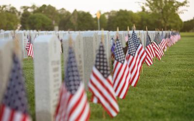 American flags in front of headstones at a cemetery
