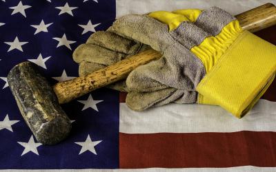 A sledgehammer and pair of gloves atop an American flag