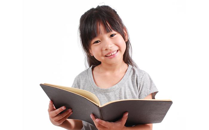 Girl holding open book in her arms