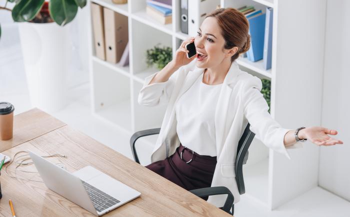 Happy businesswoman with laptop talking on cellphone