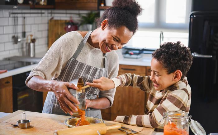 A woman and child pour filling into a pie crust