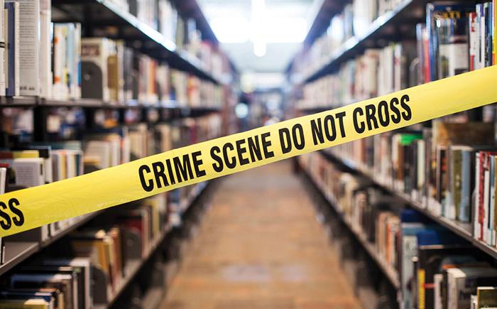 Shelves of books behind yellow crime scene tape