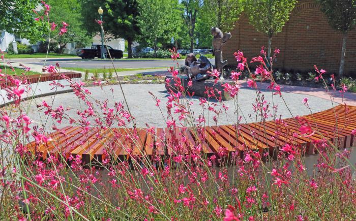 Reading with Friends sculpture and seating seen through pink flowers