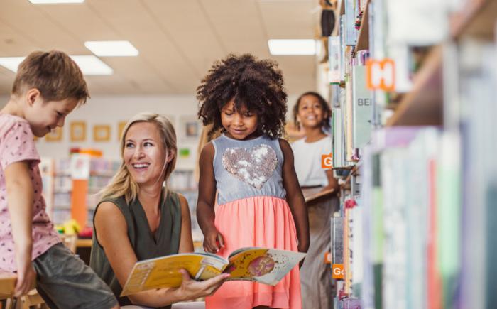 Woman holds book open for children