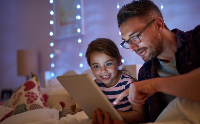 Father and daughter reading a bedtime story on a tablet