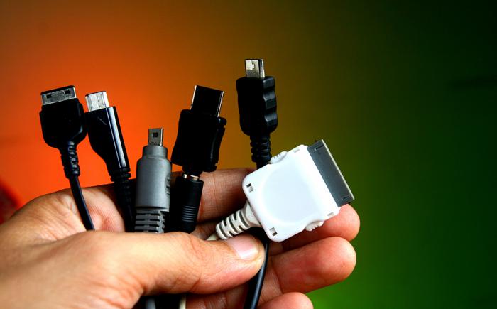 Man's hand holding a variety of charging cables