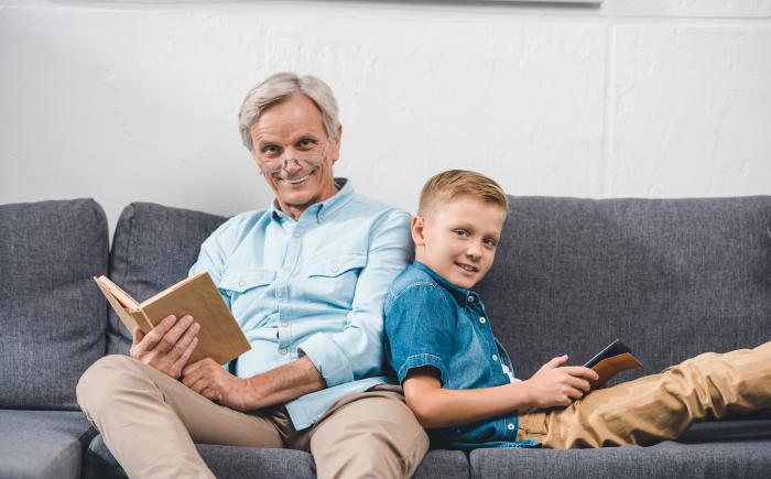Father and son sitting on couch reading