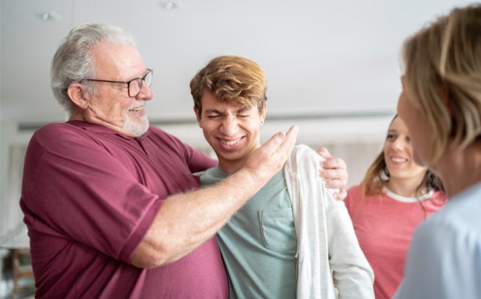 Older man hugging younger man and slapping his cheek