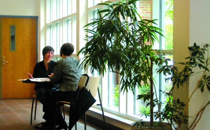 Two women seated at table in library lobby