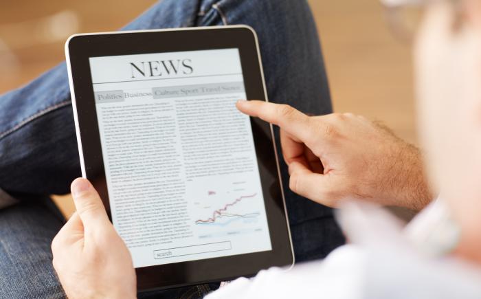 Man reading newspaper on tablet