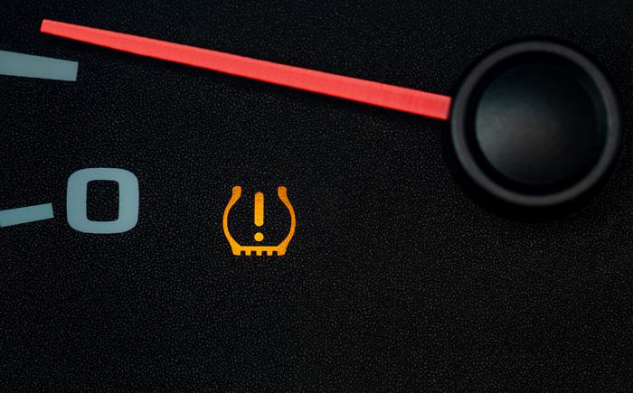 Car dashboard with low tire pressure warning light on