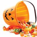 Candies spill from an overturned plastic pumpkin bucket