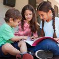 Three children looking at a book outdoors