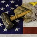 A sledgehammer and pair of gloves rest atop an American flag
