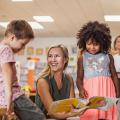 Woman holds book open for children