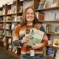 Lauren Robinson standing in front of library bookshelves holding gardening books