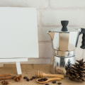 An art easel with a blank canvas and a small moka pot coffee maker