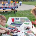 Group of children working on art projects at a table outside.