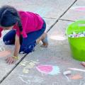 Child drawing with chalk outdoors
