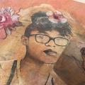 A piece of wood with an artistic, image-transferred portrait and flowers.