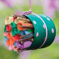A small, colorful paper bug hotel filled with rolled up pieces of paper.