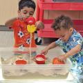 Children playing with objects in a bin of sand