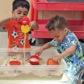 Children playing with objects in a bin of sand