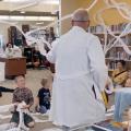 An adult in a lab coat teaching children science.