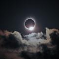 Total solar eclipse in dark sky with clouds