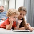 Family in living room, with kids on tablet and parents on the couch