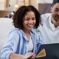 Girl sitting at laptop at home while her father looks on from behind