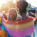 Two women wrapped in a rainbow-colored scarf