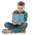 Boy sitting cross-legged reading a book