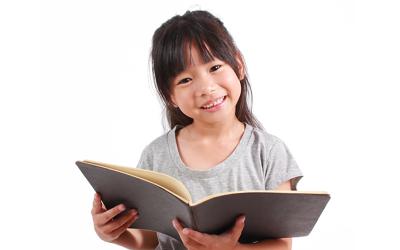 Girl holding open book in her arms