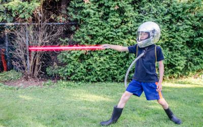 Boy holding red light saber and wearing foil covered helmet