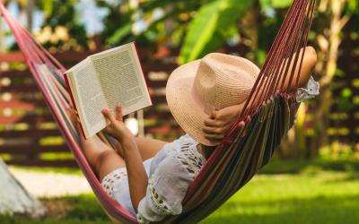 Woman in straw hat lying in hammock reading a book