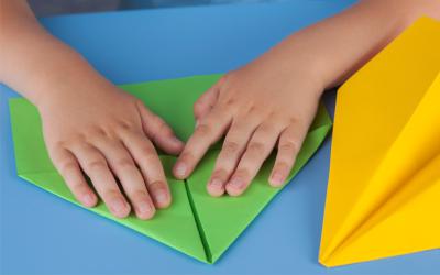 Child's hands folding a paper airplane