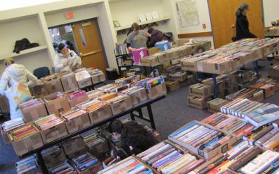 People browsing boxes of books on tables