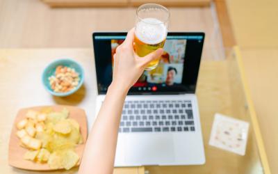 Arm in front of a laptop holding a glass and toasting