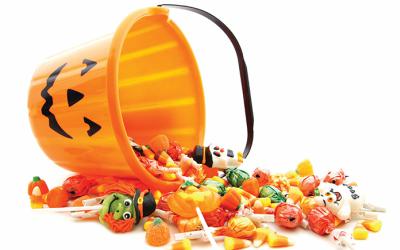 Candies spill from an overturned plastic pumpkin bucket