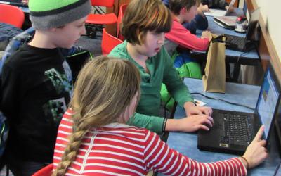 Two children working on a computer while a third looks on