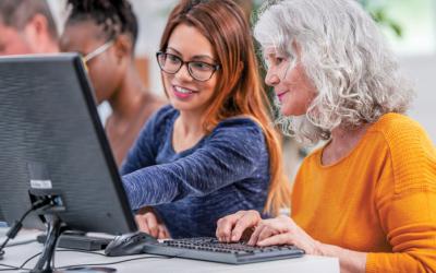 Woman points to a computer monitor while another woman sits at a keyboard