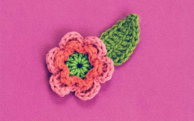 Pink yarn flower with green yarn leaf