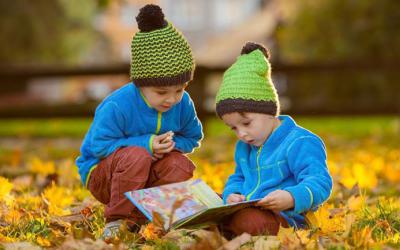 Two children reading a book outdoors
