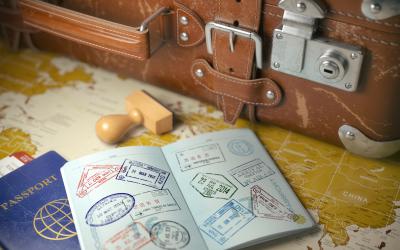 A passport and suitcase sit atop a world map