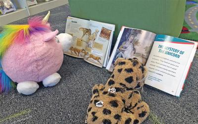 Stuffed animals looking at open books