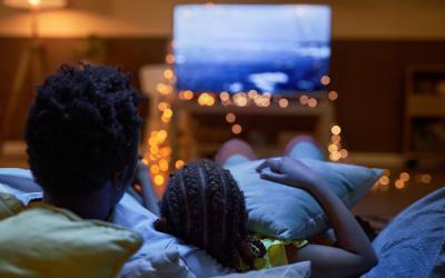 Two people sitting on couch looking at TV screen
