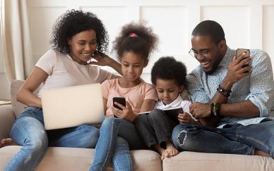 Family sitting on couch looking at devices together