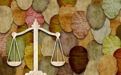 Paper collage of abstract face shapes in different tones with a scale of justice in the foreground
