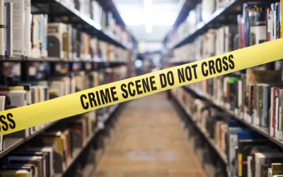 Yellow crime scene tape stretched across book shelves